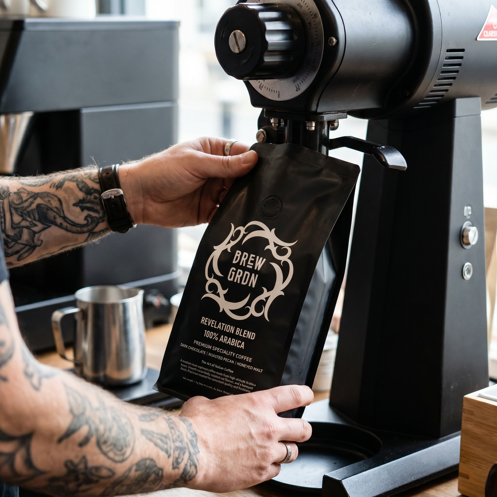Person holding a coffee bag labeled 'Brew Gran' with a coffee grinder in the background.