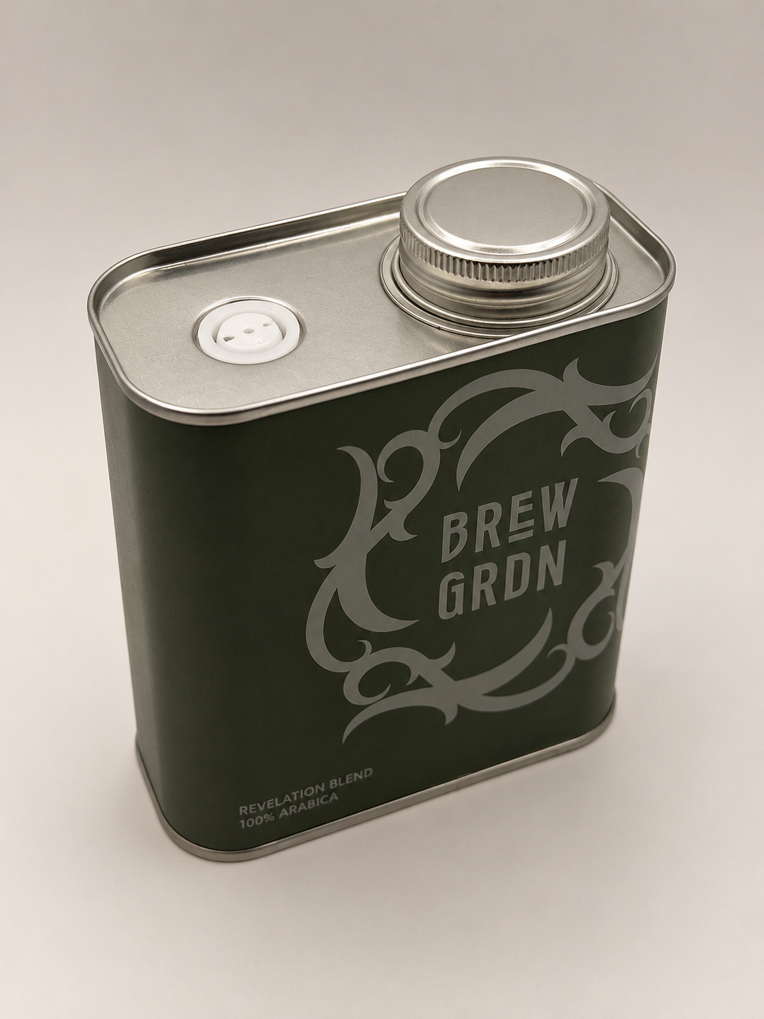 A square metal coffee canister in dark green with a silver screw cap and a silver decorative logo reading 'BREW GRDN' on the front, photographed on a light neutral background.